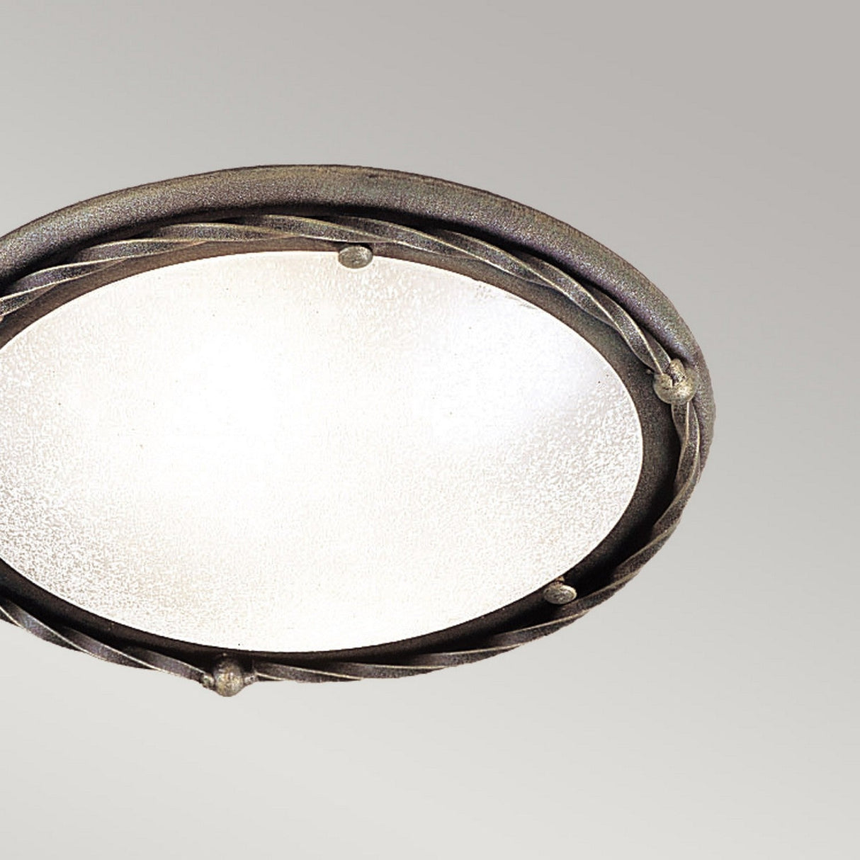 Presenting the Pembroke 1 Light Flush Light in Black/Gold: This round flush light features a textured glass surface with a decorative hand-forged iron rim. The striking black/gold finish is enhanced by twisted accents and small round details, set against a plain, soft gray background.