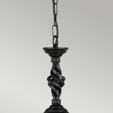 Close-up of the Pembroke 1 Light Pendant - Black, crafted from twisted hand-forged iron, hanging by a chain against a light gray backdrop. The elegant design highlights beautifully intertwined spiral elements.