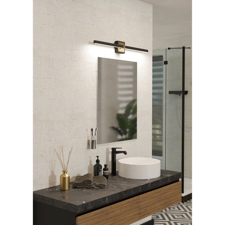 Peguera 80cm LED bathroom wall light in black with a brushed brass centre clip, mounted above a mirror over a dark marble vanity with round basin.
