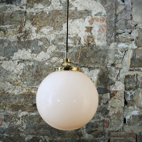 Pelagia Glass Globe Pendant Light IP44 – 35cm opal glass sphere with brass gallery and black cable, hung against a weathered stone wall.