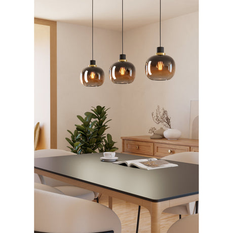 Pilmine 3-light linear pendant with smoky-to-amber glass globe shades on black cords and brass-ringed holders, hung over a dining table in a neutral-toned room.