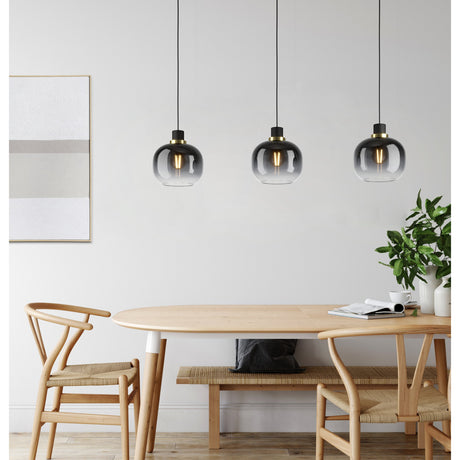 Pilmine 3-light linear pendant with smoked glass globe shades, black steel caps and brass rings, hung above a wooden dining table.