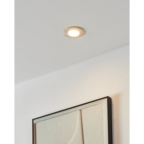 Pineda Fixed LED Downlight in satin nickel, round flush-fit design recessed into a white ceiling, shown illuminated above a framed wall artwork.