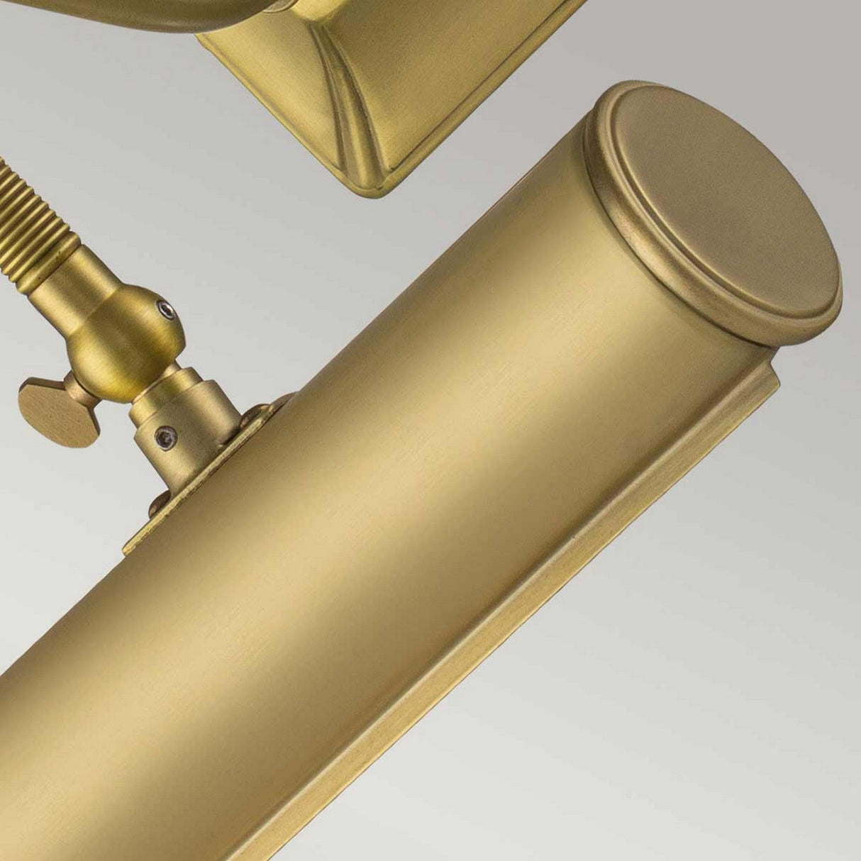 Close-up of the Picture Light 1 Light Small in brushed brass, flaunting a cylindrical wall-mounted design with an adjustable arm and metal knob for precise positioning. The fixture showcases a sleek, modern aesthetic with smooth, rounded edges.
