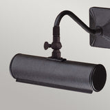 The Picture Light 1 Light Small - Black is a wall-mounted fixture designed to illuminate artwork, featuring a cylindrical shade and an adjustable arm. It includes a decorative fitting at the joint and boasts a sleek black finish with a square base for a modern appearance.