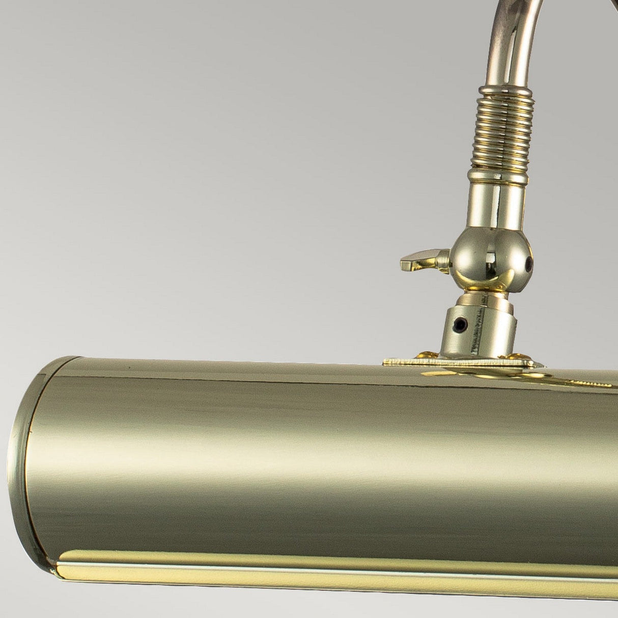 Close-up of the Picture Light 1 Light Small in a polished brass finish, featuring a cylindrical body and adjustable neck. Its glossy surface beautifully reflects light, making it an ideal choice for illuminating artwork or serving as an elegant accent light.