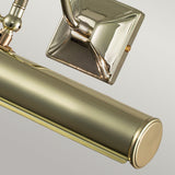 Close-up of the Picture Light 2 Light Large - Polished Brass, featuring a cylindrical shade and square backplate. Designed for artwork illumination, this lamp has a polished brass finish that reflects light beautifully, offering a sleek, modern look against a neutral backdrop.