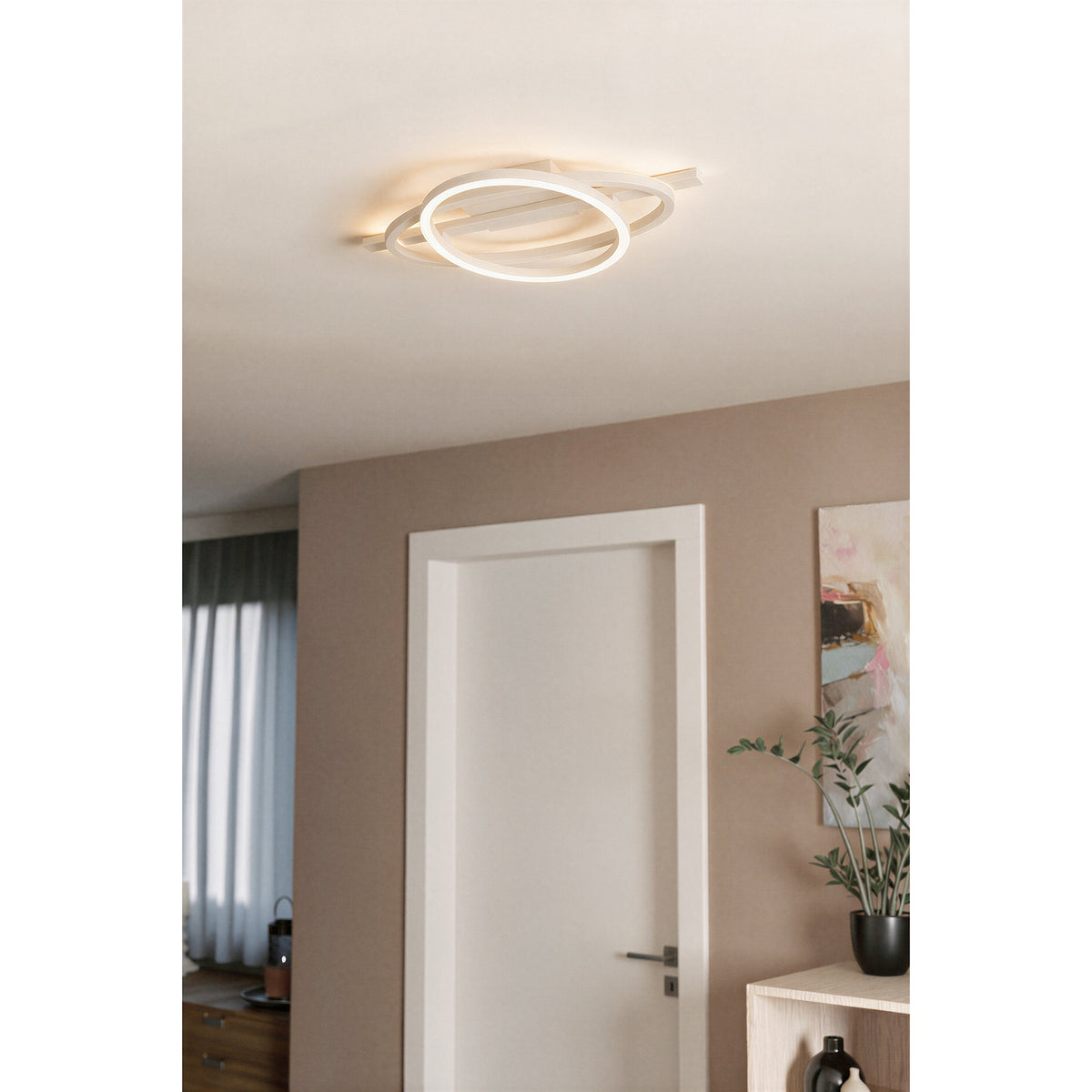 Planillo LED Flush Ceiling Light in sand finish, with crossing circular and elliptical rings and a bar, mounted on a hallway ceiling near a white door.