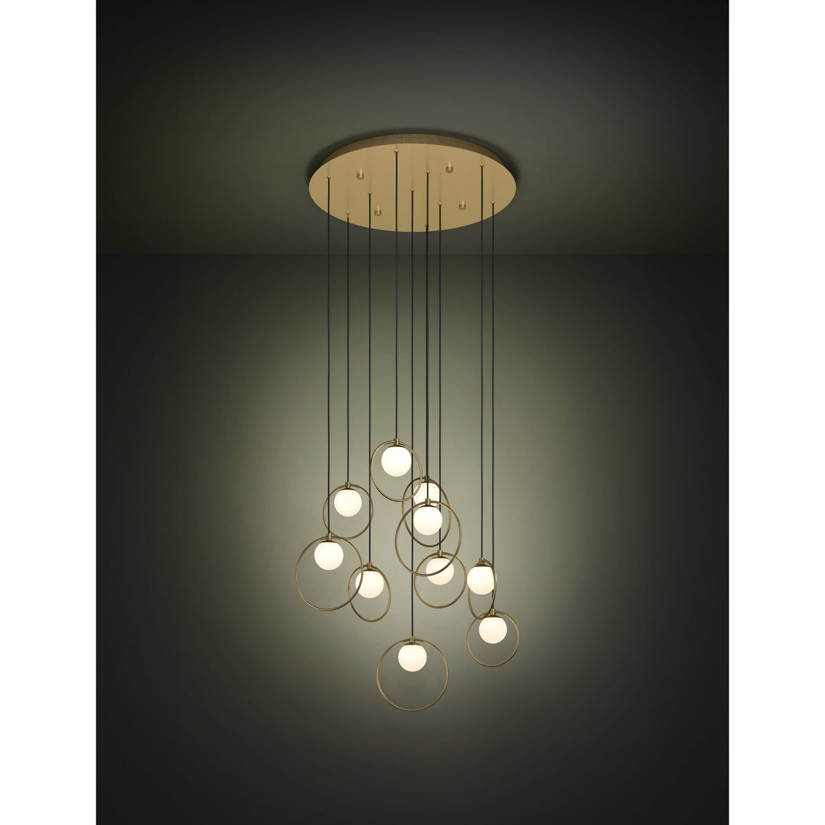 Portocolom Glass 10 Light Pendant in Brass & Gold, round ceiling plate with ten staggered black cords, gold rings holding opal glass globes, shown lit against a dark background.