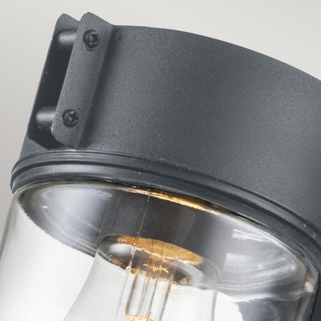 Close-up of the Portfino 1 Light Outdoor Wall Light in grey, featuring a modern nautical style with a cylindrical clear glass cover and dark metal top. The visible screws complement its robust design, and it boasts an IP44 weather resistance rating.