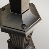 The image showcases a close-up of the Parish 1 Light Lamp Post in black, featuring a hexagonal metal structure made from die-cast aluminum. Visible screws and vertical grooves are evident on the slightly textured surface, with lighting accentuating the edges and details against a neutral backdrop, reminiscent of a sleek outdoor lamp post.