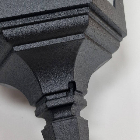 Close-up of the Parish 1 Light Outdoor Chain Pendant in black, crafted from premium die-cast aluminum. It features a geometric design with a small notch, set against a light gray background that contrasts with its matte surface. The angular features are highlighted by subtle shadows cast on the pendant's textured metal finish.