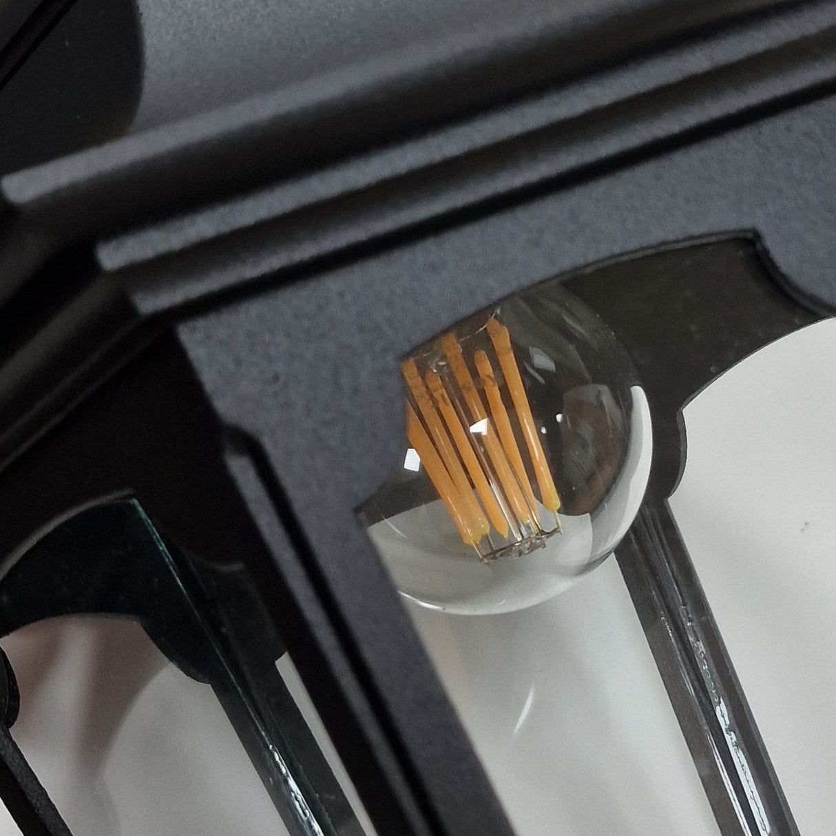 Here's a rephrased version using the product data:

Get an up-close look at the Parish 1 Light Outdoor Chain Pendant in black, expertly crafted from high-quality die-cast aluminum. Its clear glass panel showcases a retro-style LED filament bulb inside, while the detailed design of the frame enhances the modern bulb's vintage appeal.
