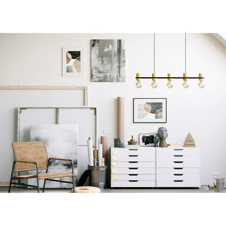 Prasvena Wooden Linear Pendant Light in black, five wooden lampholders with exposed bulbs on a slim bar, shown above a white drawer unit in a studio-style workspace.