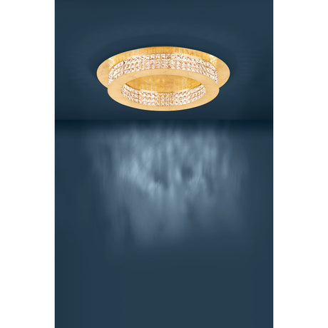 Principe LED flush ceiling light in gold, a round stepped fixture with two tiers banded in square-cut crystal, mounted on a dark blue ceiling.