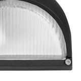 Close-up of the Prinorne outdoor wall light's black cast aluminium frame and ribbed glass shade, showing the curved hood edge and a visible fixing screw.