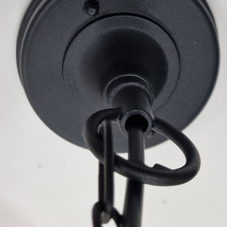 Close-up of the Parish Mini 1 Light Outdoor Chain Pendant in black metal, featuring a sleek black powder coating. The chain elegantly loops through a rounded hook on the fixture, set against a white ceiling background to enhance the ambient lighting of the space.