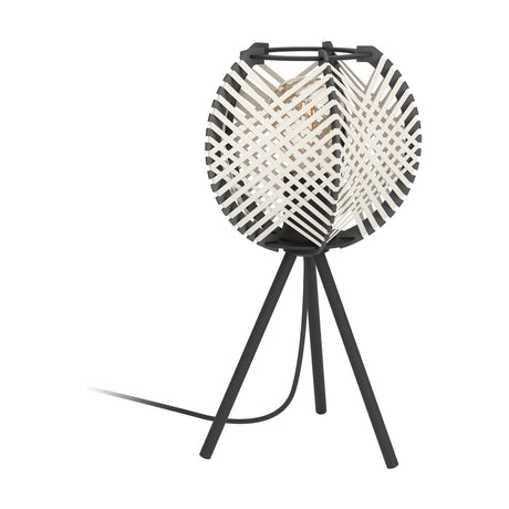 Prosena table lamp with a round woven shade of crossed black and white straps in a black frame, set on a black steel tripod base, shown on a plain white background.