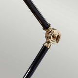 Close-up of two metallic rods connected by the polished brass joint of the Provence Element 1 Light Mini Table Lamp, set against a light gray background. The shiny joint contributes a French-inspired design to the composition, with one rod angled upward and the other extending downward, evoking an elegant Provence element.