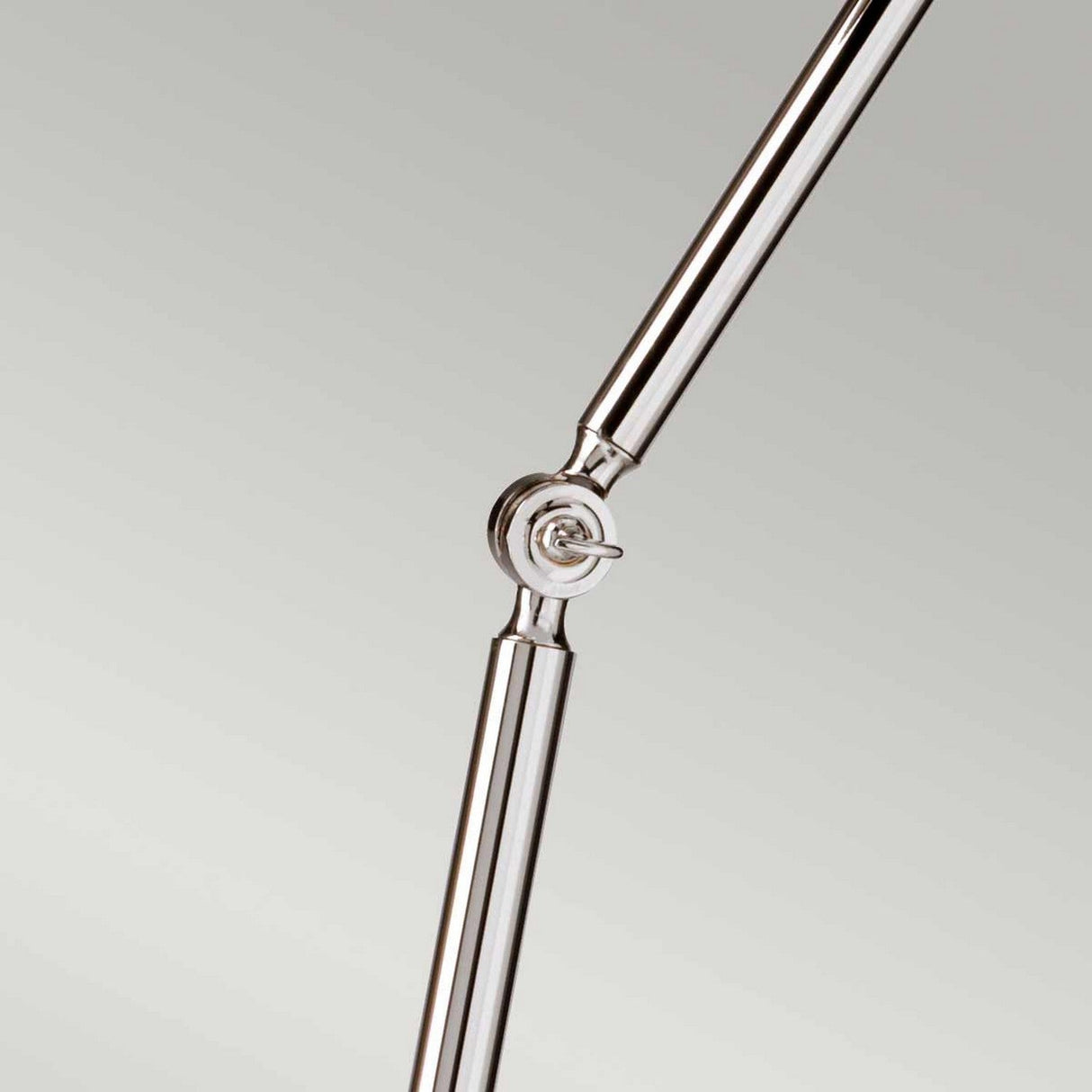 A close-up of a polished nickel joint on the sleek, shiny Provence 1 Light Floor Lamp reveals its modern, minimalist design. The adjustable knuckle joints provide rotation and flexibility, standing out against a plain background.