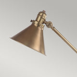 The Provence 1 Light Table Lamp in aged brass features a conical shade and provides versatile lighting to meet your needs. This elegant piece stands gracefully against a neutral gray background, merging timeless charm with functionality.