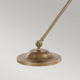 The Provence 1 Light Table Lamp - Aged Brass features a close-up view of its elegant design, showcasing a vintage charm with its round, flat shade on an adjustable arm. The shade has a sleek and simple appearance, and the joint allows for precise angle adjustments. Set against a plain light gray background, this lamp embodies timeless elegance and functionality.
