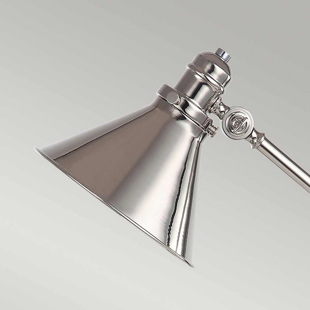 Close-up of the Provence 1 Light Table Lamp in polished nickel, featuring adjustable joints and a conical shade, set against a light gray background. The lamp's reflective surface catches the light, highlighting its modern design.