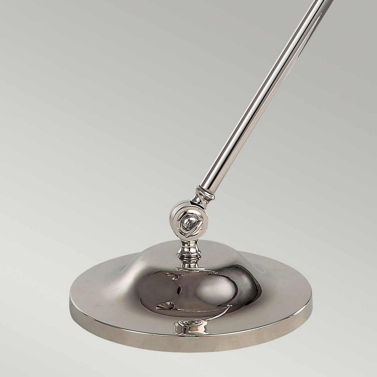 A close-up of the Provence 1 Light Table Lamp in polished nickel showcases its sleek, adjustable arm and round base. Its reflective metal surface stands out against a plain, light gray background, highlighting the elegantly crafted adjustable joints for perfect illumination.