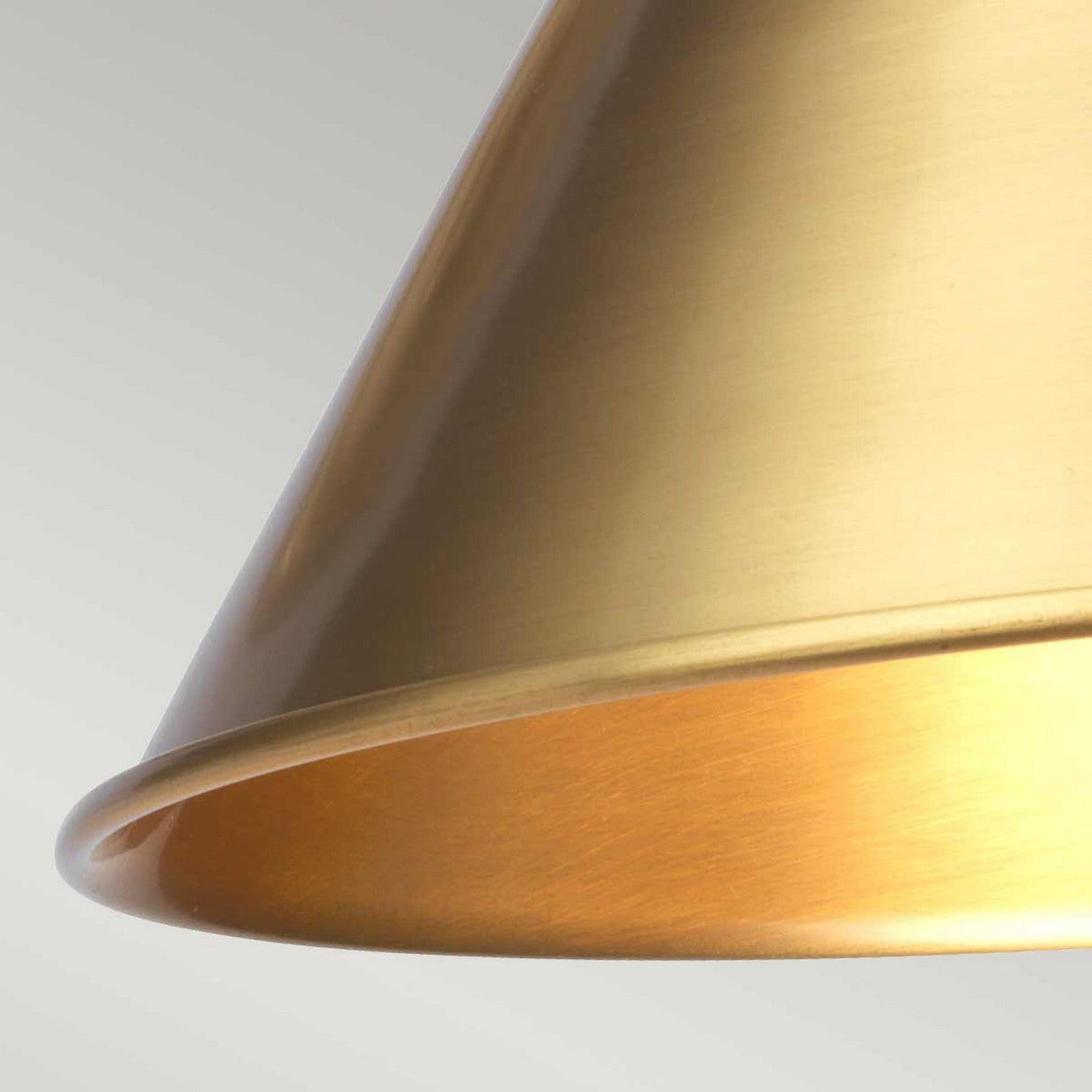 Close-up of the Provence 1 Light Wall Light in aged brass, featuring a metallic, gold-colored lampshade set against a light gray background. The lampshade displays a smooth, conical design that captures a warm, reflective sheen.