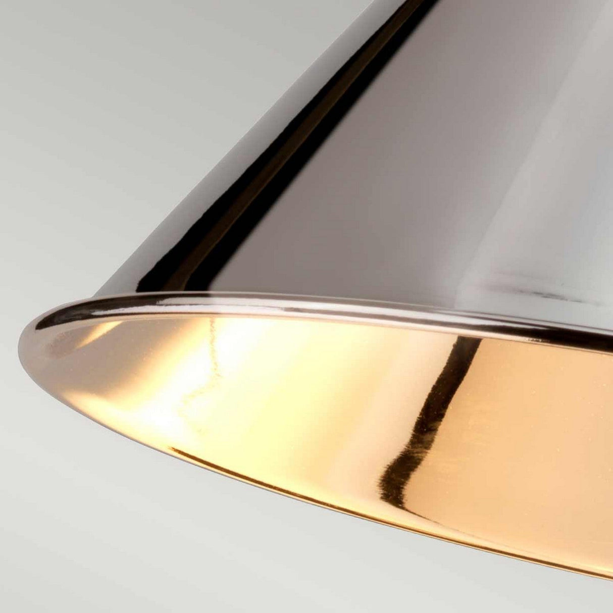 Close-up of the Provence 1 Light Wall Light in polished nickel, featuring a modern metallic lampshade with a smooth, reflective surface. The interior emits a warm, golden glow that emphasizes its sleek design and adjustability against a pale background.