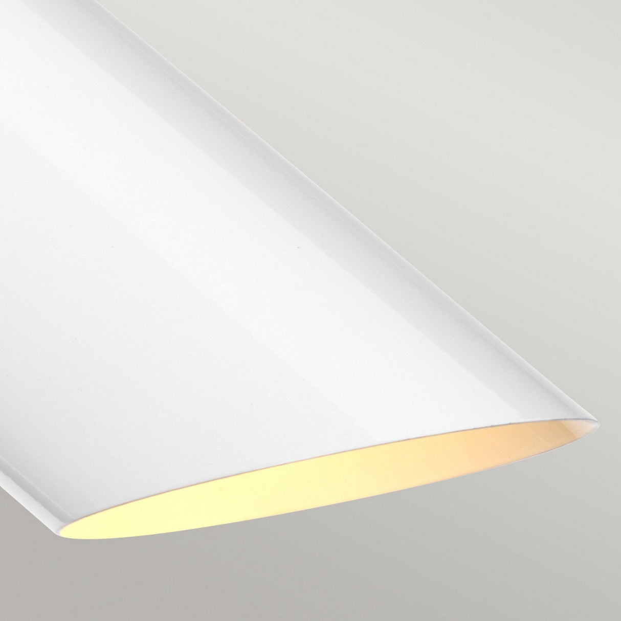 A close-up of the Quinto 1 Light Table Lamp in white and aged brass reveals a sleek, modern curved fixture that casts a soft, warm glow against a pale gray background. This minimalist design highlights smooth lines and simple elegance.