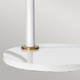 Close-up of the Quinto 1 Light Table Lamp - White/Aged Brass featuring a sleek, round white base with a minimalist design. A subtle aged brass accent elegantly divides the base and pole, set against a light gray background.