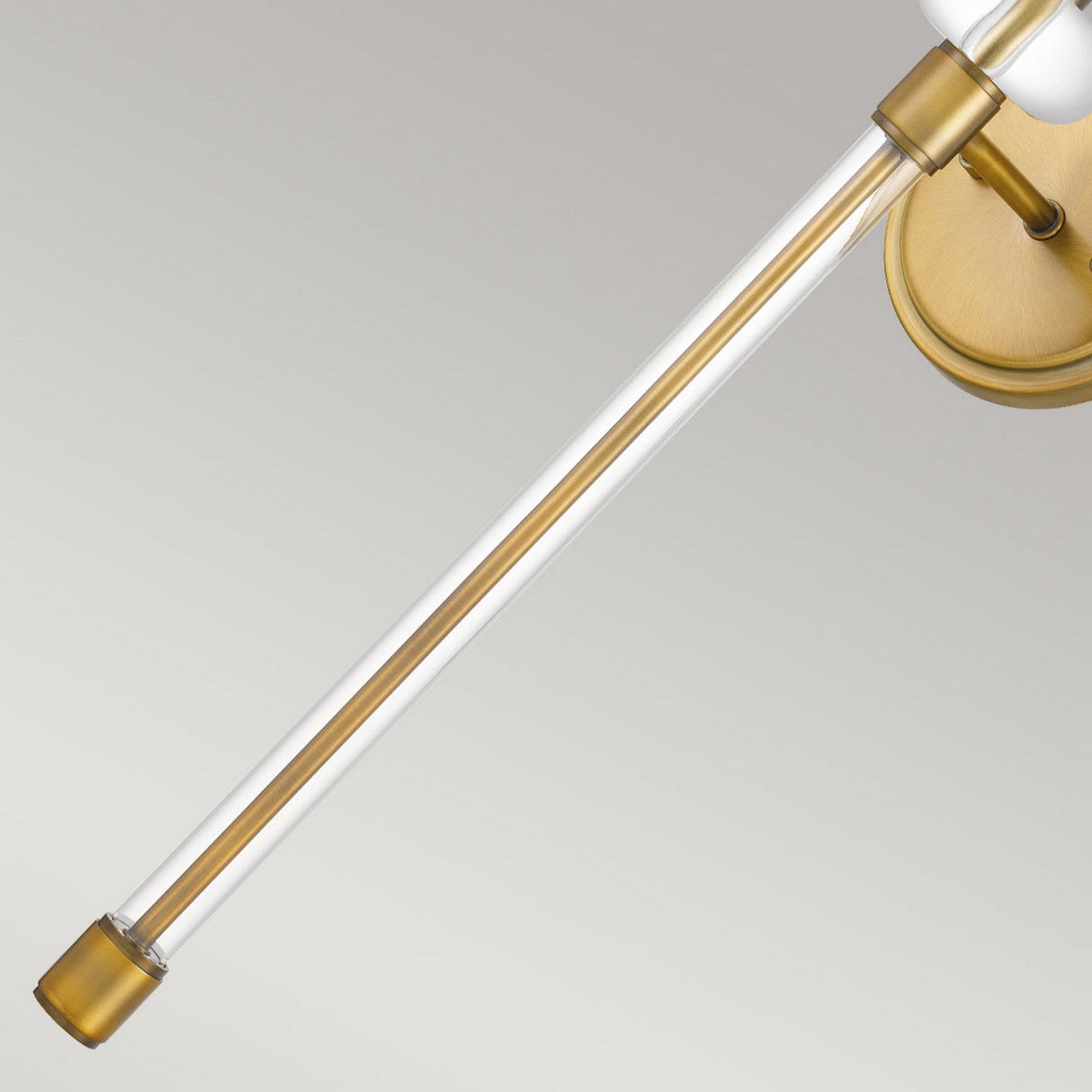 The Barbour 1 Light Wall Light in Weathered Brass features a contemporary design with a long, sleek arm that angles gracefully from the wall. It supports a cylindrical bulb encased in clear glass, offering a vintage charm and elegant look against the gray backdrop.