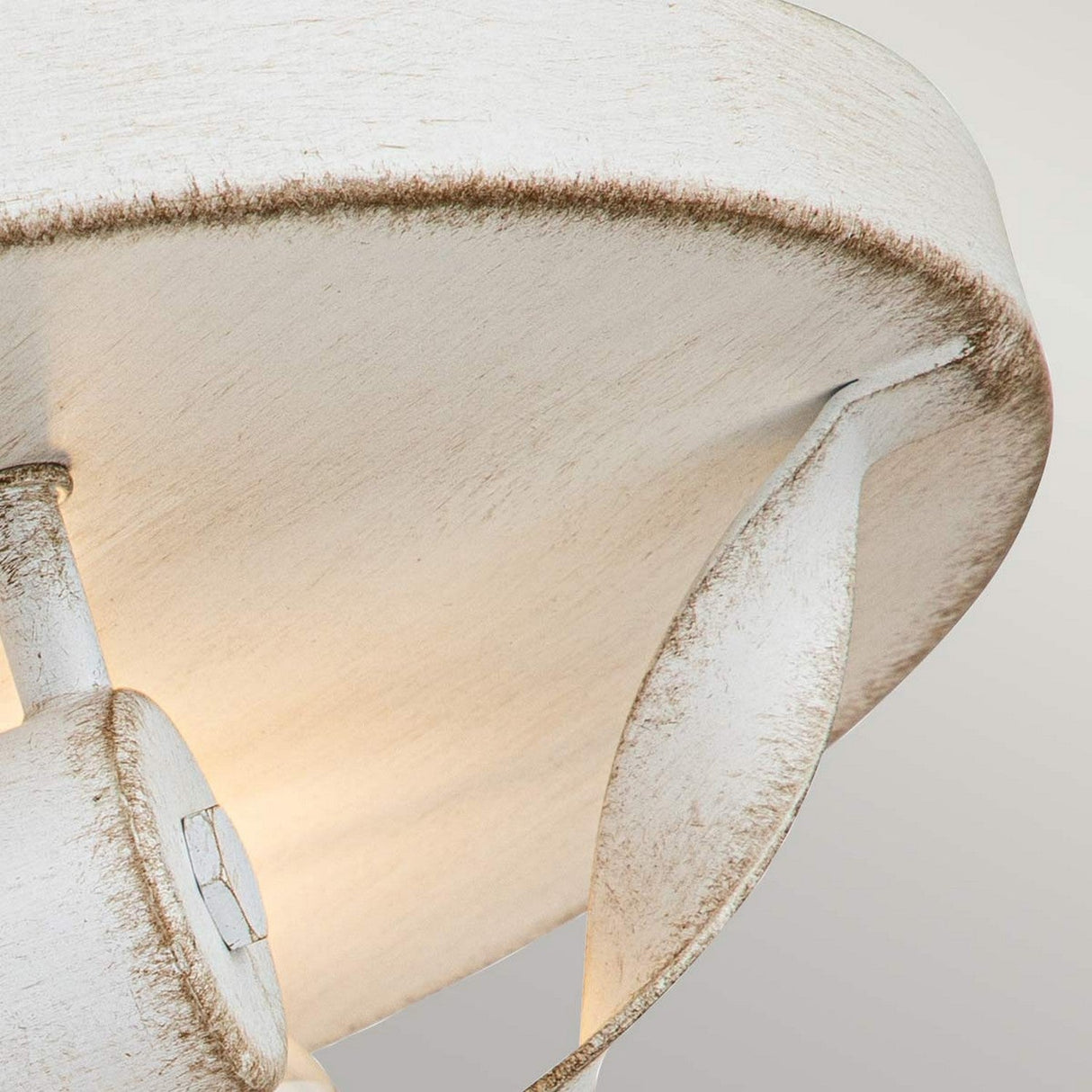 A close-up view of the Bradbury 2 Light Flush in Antique White showcases its distressed finish, curved leaf-like detailing, and a wide, shallow shade. The texture and minimalist design lend it a charming vintage appeal.