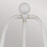 Close-up of the Bradbury 2 Light Wall Light in antique white, featuring a weathered decorative iron design that resembles an abstract figure with a round head and arched arms, set against a plain, light background.