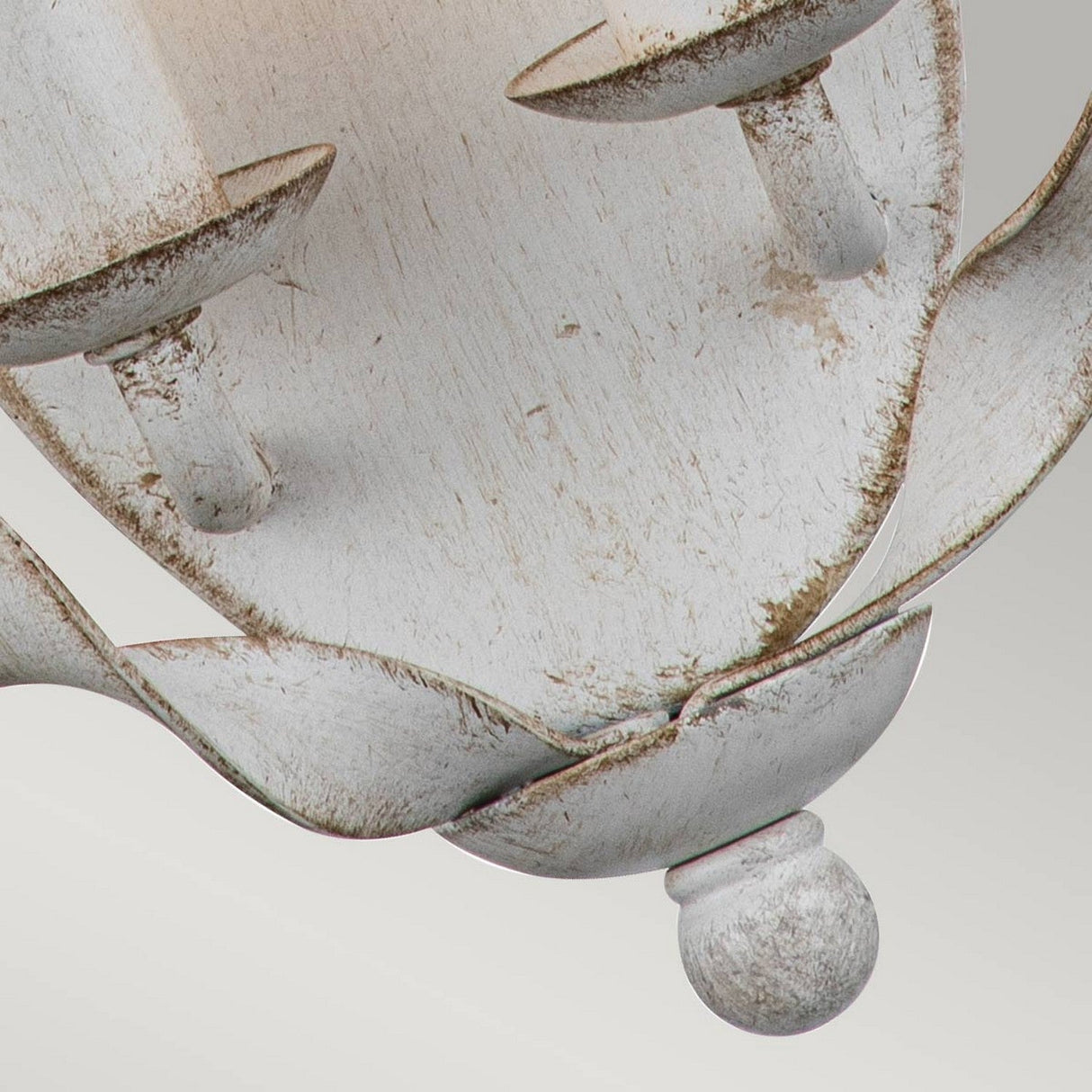 A close-up of the Bradbury 2 Light Wall Light in antique white, showcasing its vintage and weathered charm. The metal surface features visible rust and patina, enhancing its timeless allure. With a dual light design, attention is drawn to the base and two candle holders, reflecting an elegant bygone era.