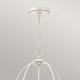 A close-up of an overhead light fixture exudes vintage charm with its rustic metal chain supporting an open, cage-like frame. The Bradbury 5 Light Chandelier - Antique White showcases a distressed finish, beautifully contrasting against a smooth, light gray background.