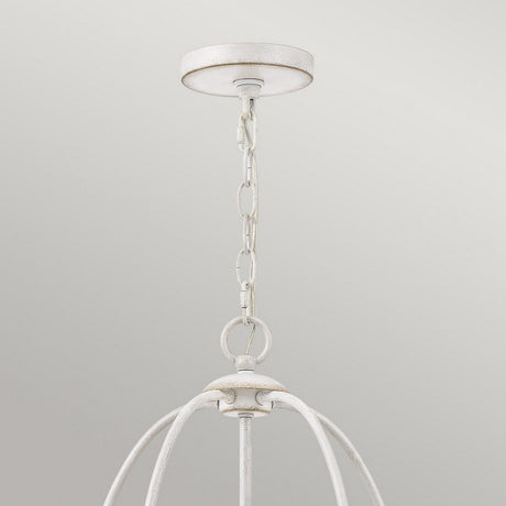 A close-up of an overhead light fixture exudes vintage charm with its rustic metal chain supporting an open, cage-like frame. The Bradbury 5 Light Chandelier - Antique White showcases a distressed finish, beautifully contrasting against a smooth, light gray background.
