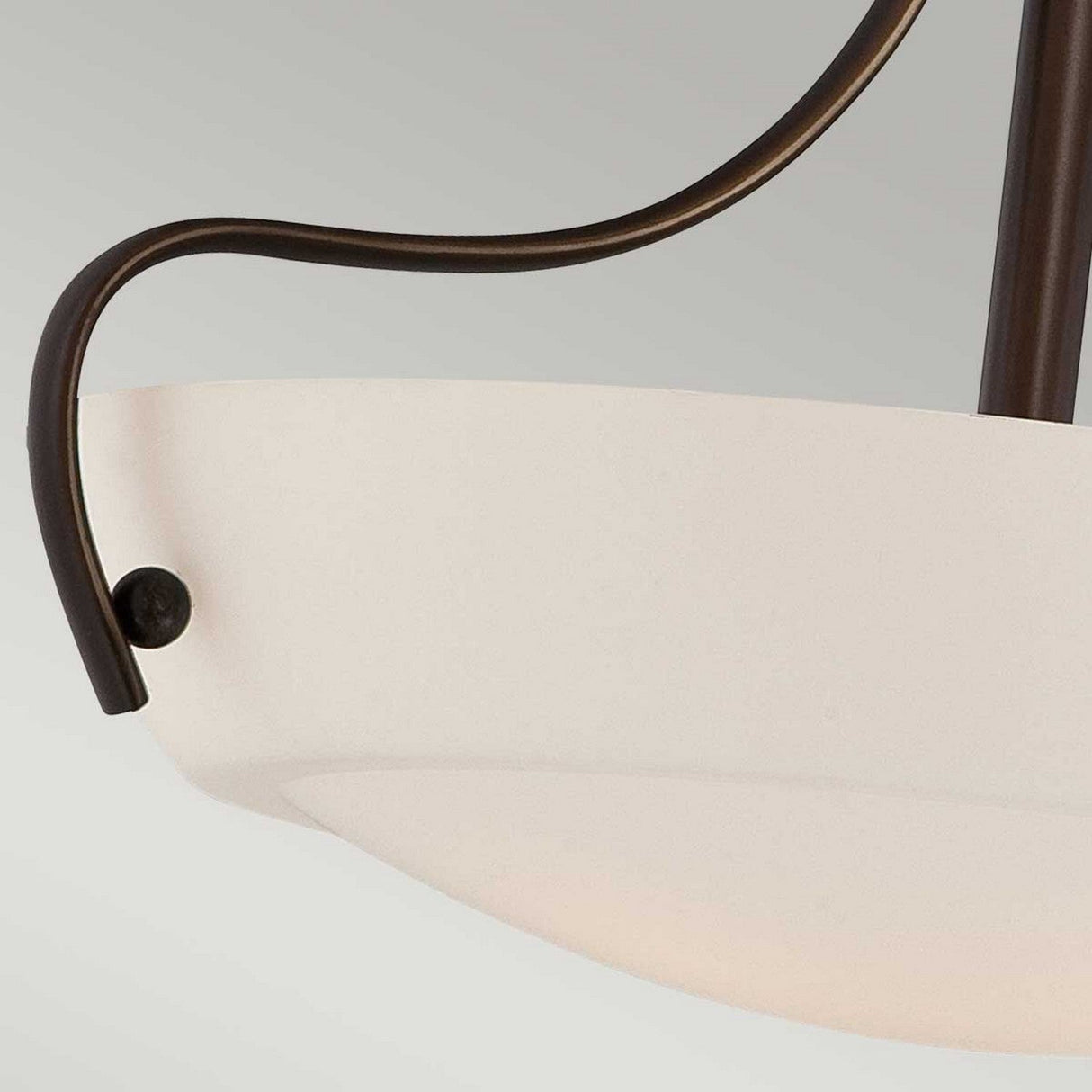 Close-up of a Chantilly 3 Light Semi-Flush in bronze, showcasing a modern ceiling light fixture with an opal-etched glass diffuser. The design features simple, curved lines and a minimalist aesthetic against a light gray background.