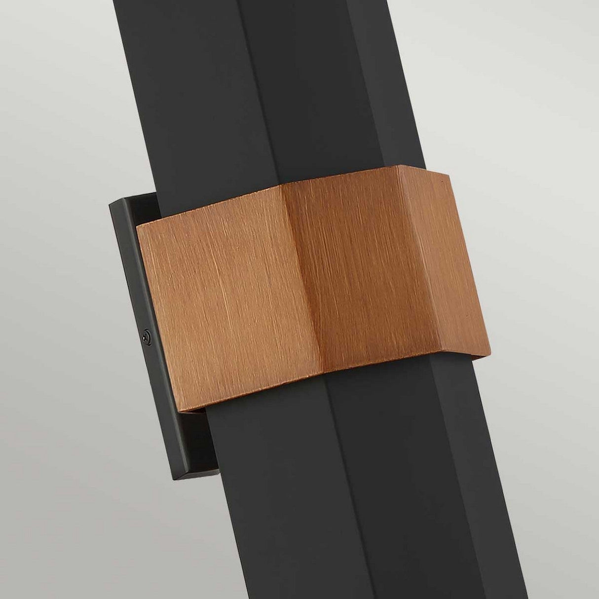 Introducing a detailed view of the Chasm Outdoor LED Large Wall Lantern in a sophisticated matte black finish. This fixture boasts an integrated LED technology and features a sleek rectangular frame with a central copper-colored accent. Its minimalist design delicately harmonizes industrial and elegant elements, set against a neutral backdrop.