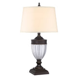 The Dennison 1 Light Table Lamp in Palladian Bronze showcases a textured glass body with a cream-colored shade, elegantly positioned on an ornate base, making it ideal for enriching Transitional Interiors.