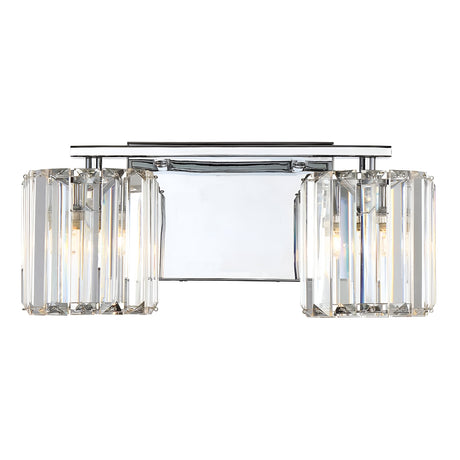 The Divine 2 Light Wall Light - Polished Chrome is a modern wall sconce featuring two cylindrical lampshades adorned with crystal accents, each housing a light bulb. Its elegant design incorporates polished chrome and crystal glass slats, offering a luxurious and contemporary ambiance.