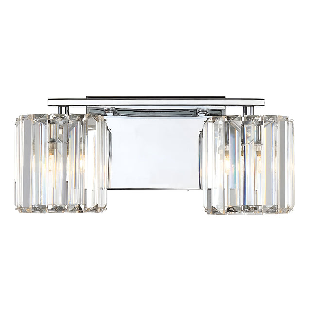 The Divine 2 Light Wall Light - Polished Chrome is a modern wall sconce featuring two cylindrical lampshades adorned with crystal accents, each housing a light bulb. Its elegant design incorporates polished chrome and crystal glass slats, offering a luxurious and contemporary ambiance.