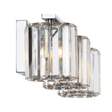 The Divine 3 Light Wall Light - Polished Chrome showcases a contemporary wall sconce design with a polished chrome finish and crystal glass accents. It features three cylindrical glass shades arranged in a linear format, providing bright illumination while maintaining an elegant and sleek appearance.