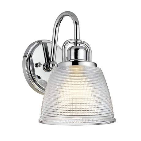 The Dublin 1 Light Wall Light in polished chrome features a ribbed glass shade that emits a warm glow. Its design includes a curved arm connecting the round wall mount to the light fixture, seamlessly blending vanity lighting with modern and classic aesthetics, making it perfect for bathroom lighting.
