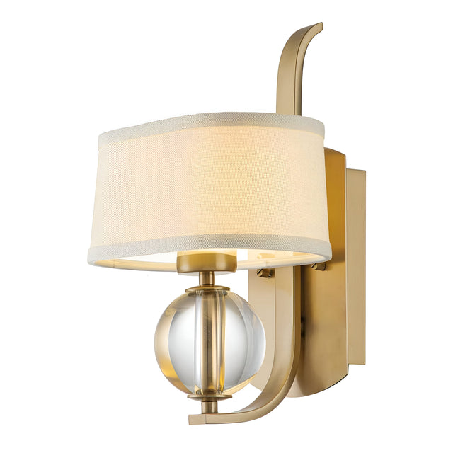 Introducing the Gotham 1 Light Wall Light - Brushed Brass, a modern wall sconce with a sleek gold metal frame. It showcases a cylindrical beige fabric shade and is adorned with a decorative glass orb beneath. This elegant design seamlessly merges contemporary and classic elements, making it an ideal choice for modern interiors.