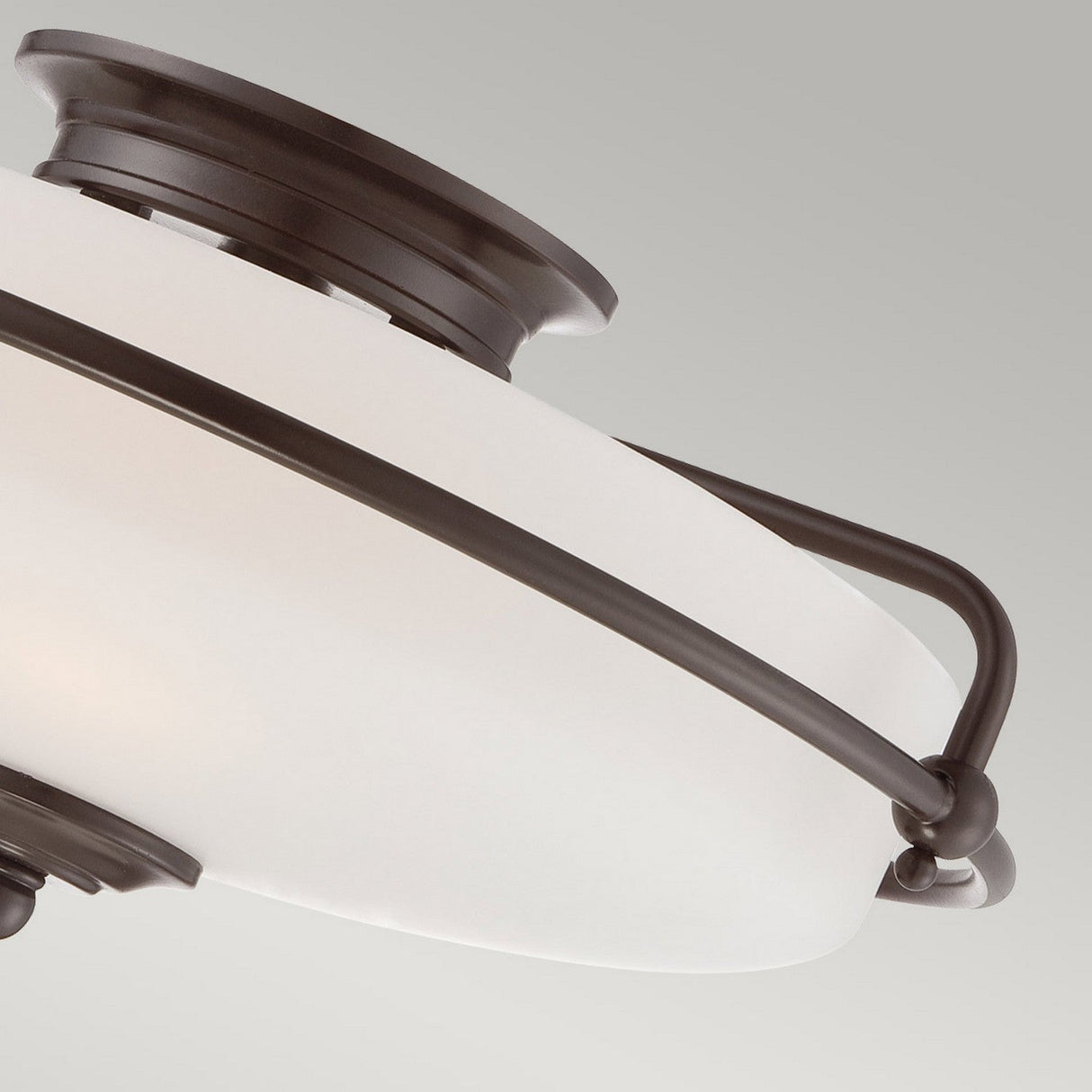 A close-up of the Griffin 3 Light Flush - Palladian Bronze ceiling light fixture showcases its etched glass shade nestled within a Palladian Bronze frame, offering a modern and sleek appearance against a light grey background.