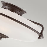 A close-up of the Griffin 3 Light Flush - Palladian Bronze ceiling light fixture showcases its etched glass shade nestled within a Palladian Bronze frame, offering a modern and sleek appearance against a light grey background.