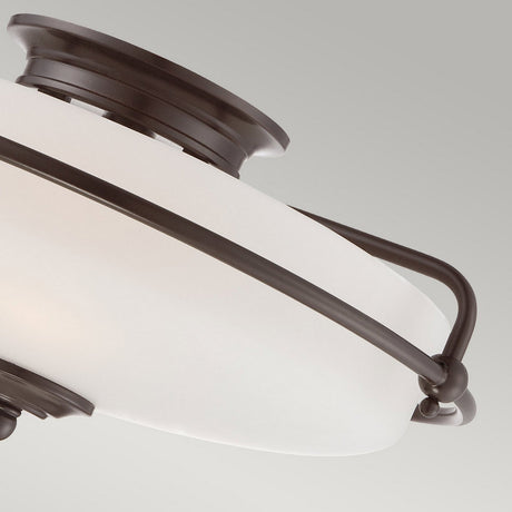 A close-up of the Griffin 3 Light Flush - Palladian Bronze ceiling light fixture showcases its etched glass shade nestled within a Palladian Bronze frame, offering a modern and sleek appearance against a light grey background.