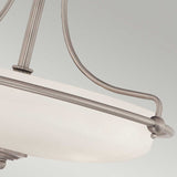 A close-up view of the Griffin 3 Light Semi-Flush in Antique Nickel showcases its modern ceiling light design. With a frosted glass shade, sleek metal rods extending from the center, and a smooth curved edge, it serves as an ideal choice for contemporary interiors set against a neutral background.